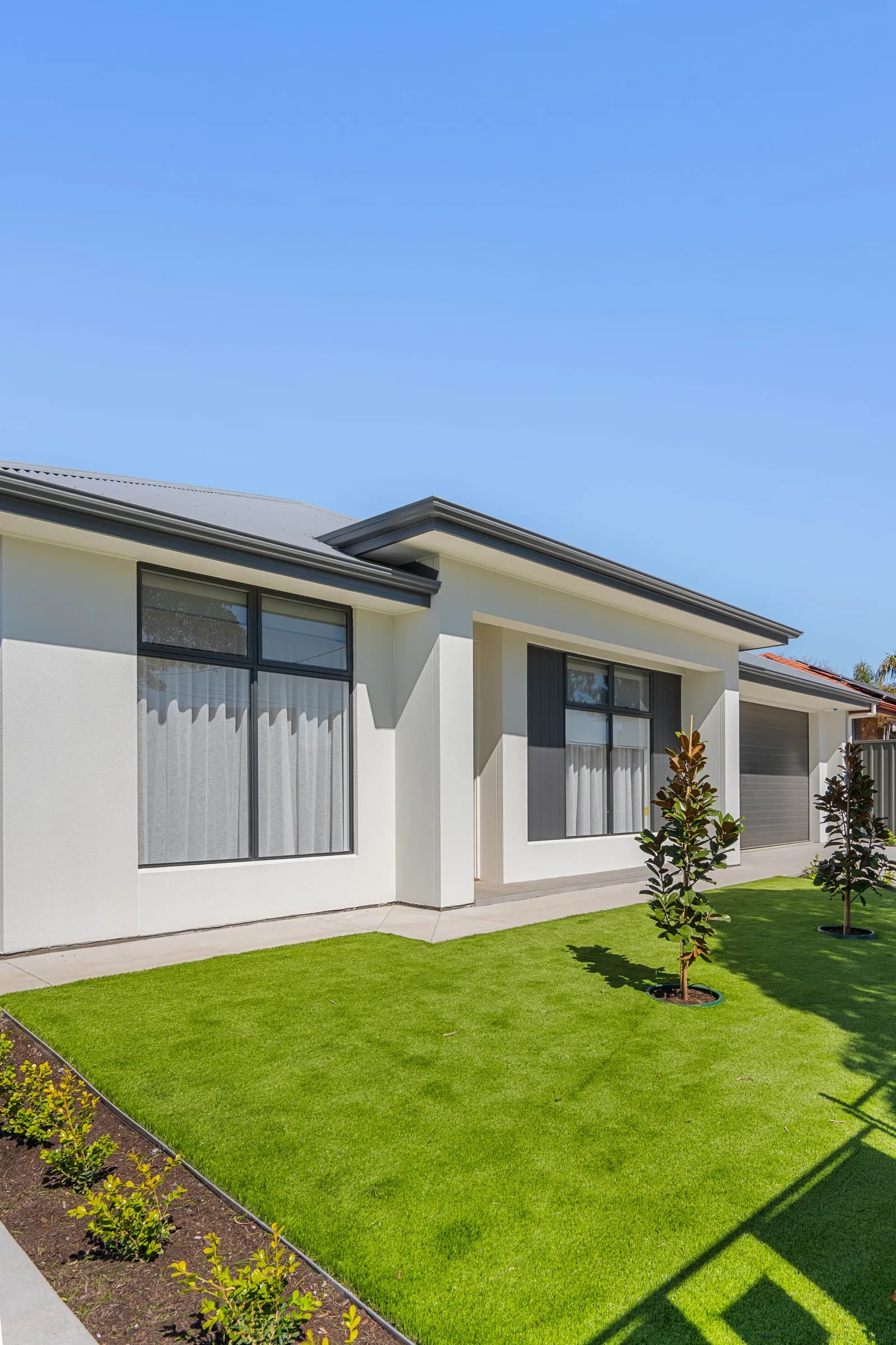 Rendered front facade of a single-storey home in Queenstown under a clear sky