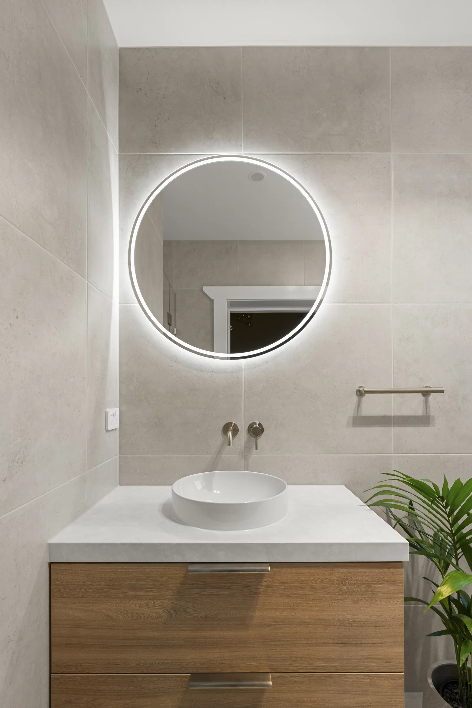 Vanity with a backlit round mirror and wall-mounted tapware