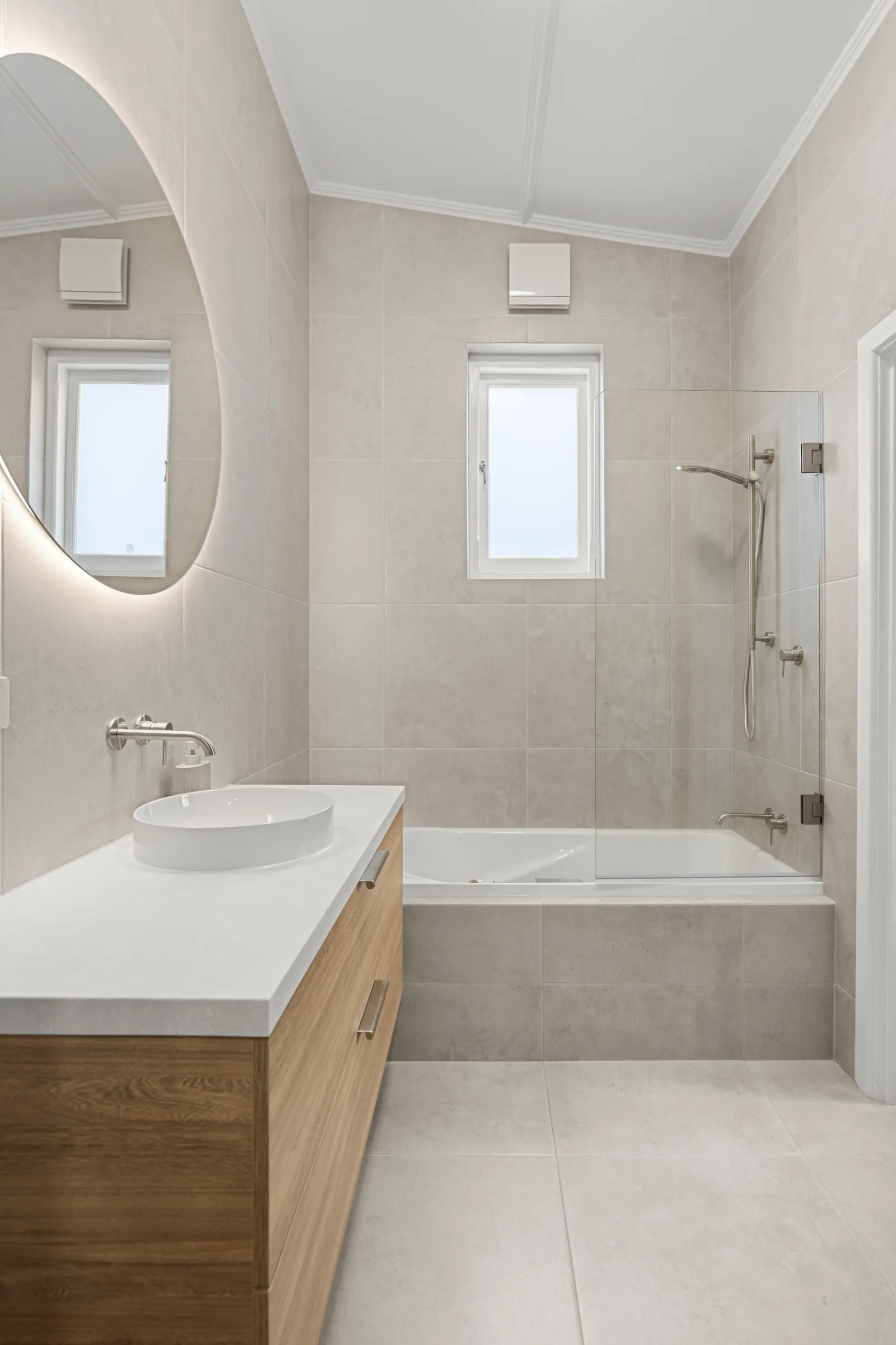 Renovated bathroom with a bath, glass screen and floating vanity