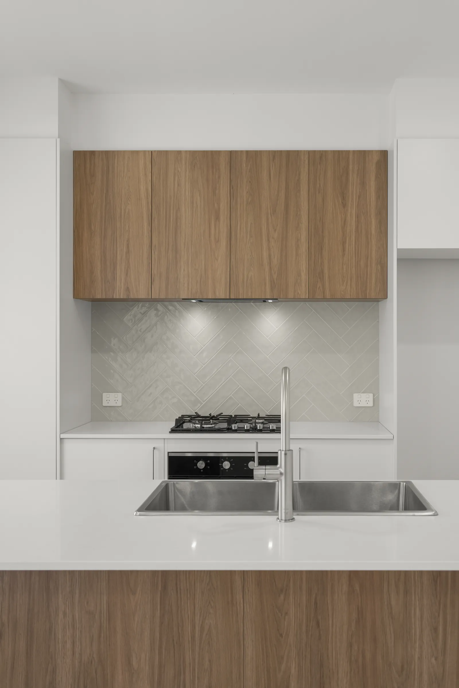 Herringbone tiled splashback and timber-look overhead cabinets