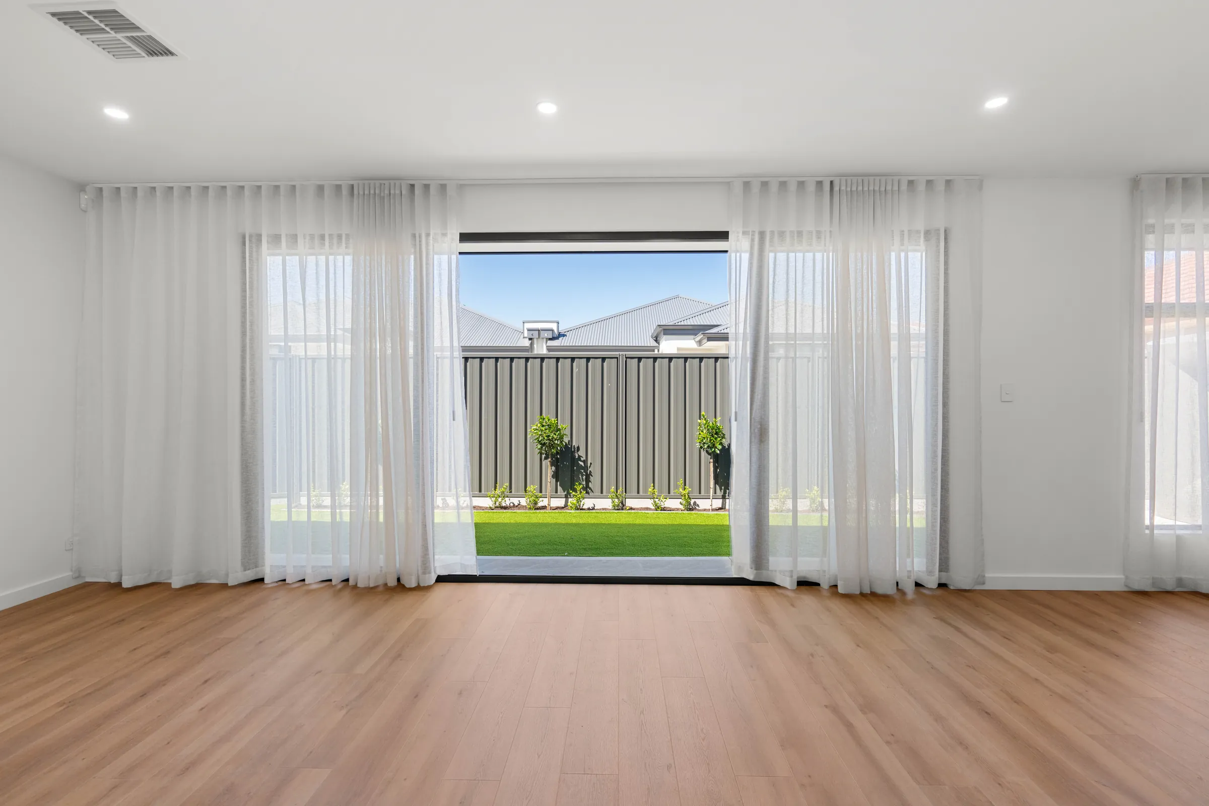 Living area with timber-look flooring and sliding doors to the rear yard