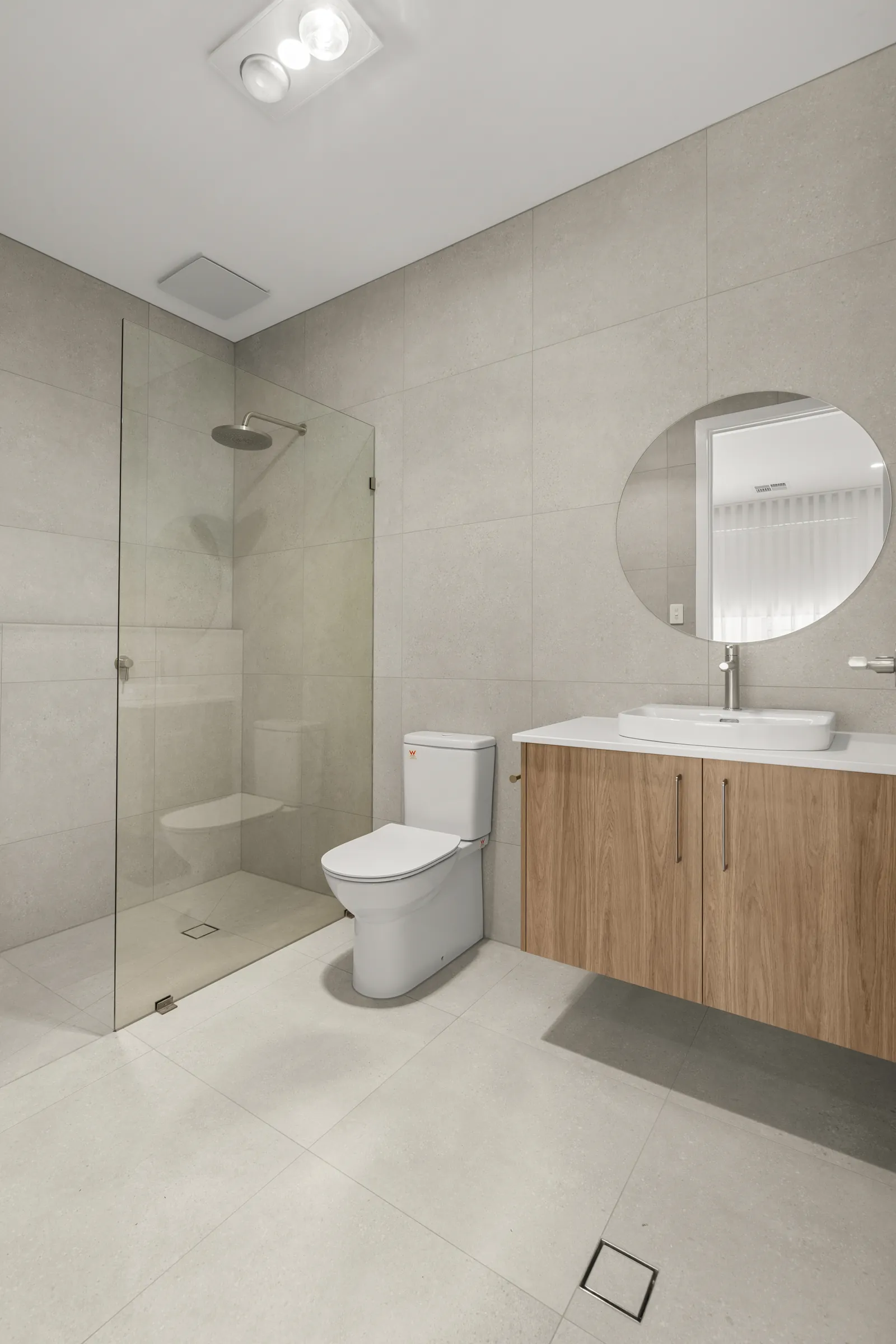 Bathroom with a walk-in shower, floating timber-look vanity and round mirror