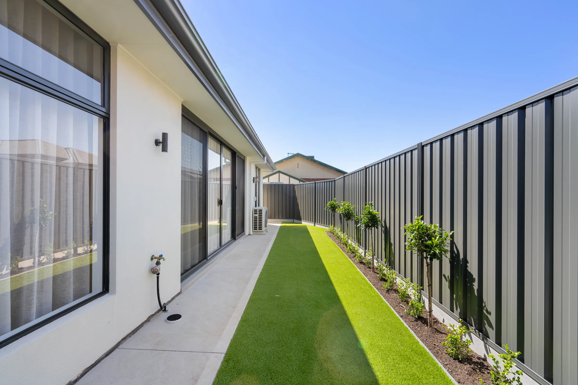 Side yard with a paved path, low-maintenance lawn and Colorbond fencing